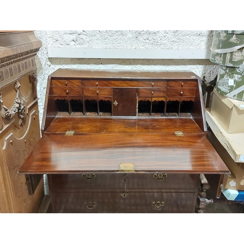 1084 - A George III period mahogany slope front Bureau, with fitted interior above three long drawers on br... 