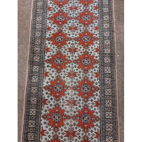 1117 - An antique style Middle Eastern Carpet / Runner, the grey ground with multiple red medallions with s... 