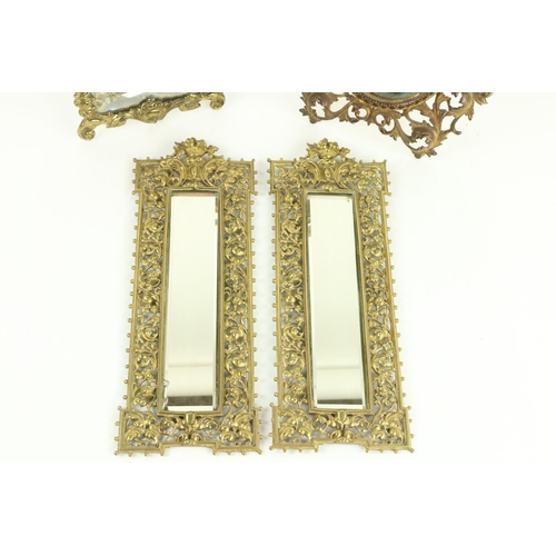 606 - A pair of tall narrow brass Wall Mirrors, each with ornate gilt brass open work frame crested with f... 