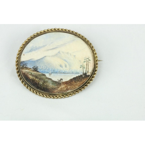 746 - A 19th Century oval Brooch, the inset painted with view of Mountainous Lake Scene, horse drawn carri... 