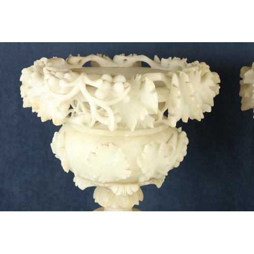 878 - A fine pair of 19th Century alabaster Urns on stands, each urn with carved floral sprays on conformi... 