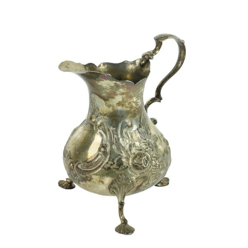 636 - A small English Victorian silver Cream Jug, decorated with scrolls, flowers and leaves, on three pad... 