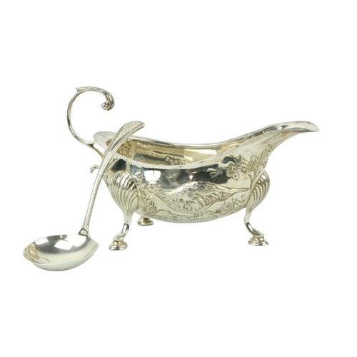 665 - An Irish silver Sauceboat, Dublin 1977, chased with pheasants in a landscape on three shell and pad ... 