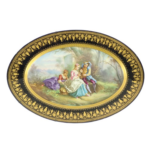 259 - A large oval Serves style porcelain Platter, depicting three figures in a garden landscape, inside a... 