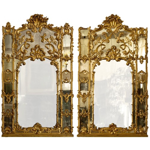 A magnificent and large pair of Irish carved giltwood compartmental Console Mirrors, attributed to James Hicks of Dublin, each crested with stylised shell and flowers, the upper plate applied with leaf scrolls and floral design in high relief, the lower sections with two plates headed with an anthemion crest and further scrolls, the lower two panels within a rustic frame, the outer panels with trellis work and interlaced ribbons and foliage, each approx. 8' high x 57" wide (244cms x 146cms). (2)