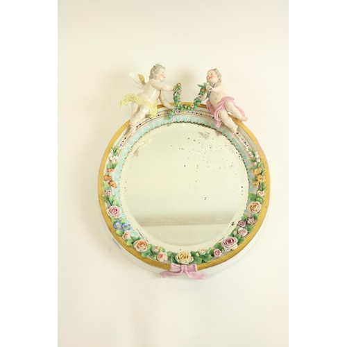 394 - An oval German porcelain flower encrusted Wall Mirror, probably Sitzendorf crested with two cherubs ... 