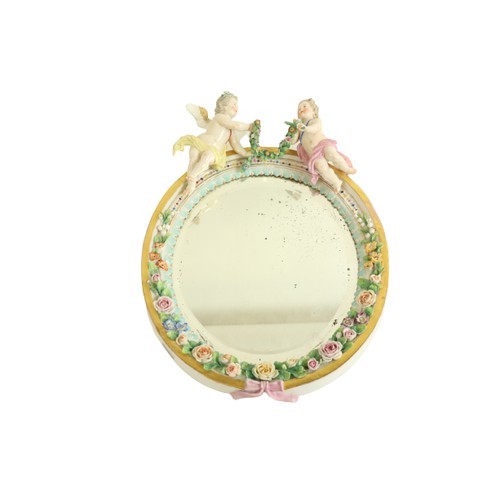 394 - An oval German porcelain flower encrusted Wall Mirror, probably Sitzendorf crested with two cherubs ... 