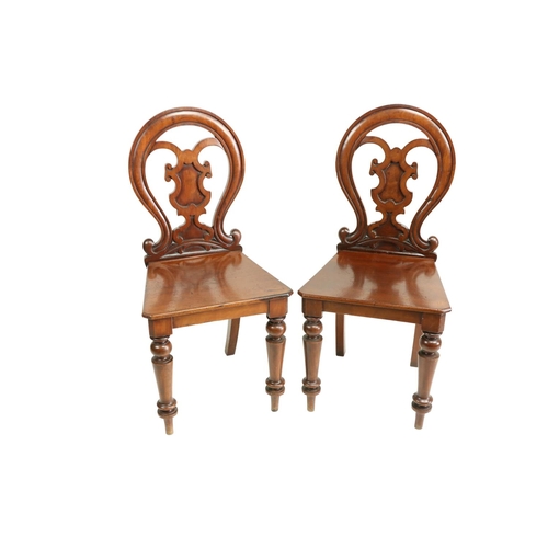 628 - A pair of Victorian mahogany Hall Chairs, each with open work cartouche shaped back above a solid se... 