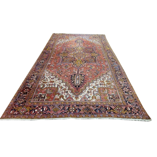 685 - A Persian Heriz Carpet, the iron red field with a centre medallion and all over pattern with ivory s... 