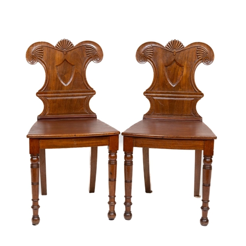 188 - A fine pair of George IV period Irish mahogany Hall Chairs, each with shield shaped backs and centra... 