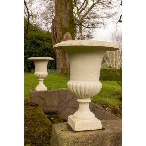 549 - A pair of campana shaped cast iron Garden Urns, each with half reeded body on stem base, 61cms ... 