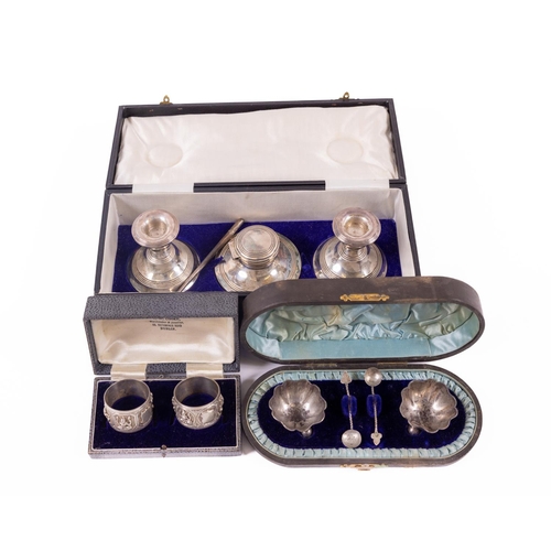 73 - A cased silver Desk Set, comprising a pair of Candlesticks, London 1924, a matching Pot and a pen, t... 