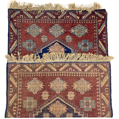 726 - An Afghan Rug, the burgundy ground with a large dark blue three stage medallion inside a single bord... 