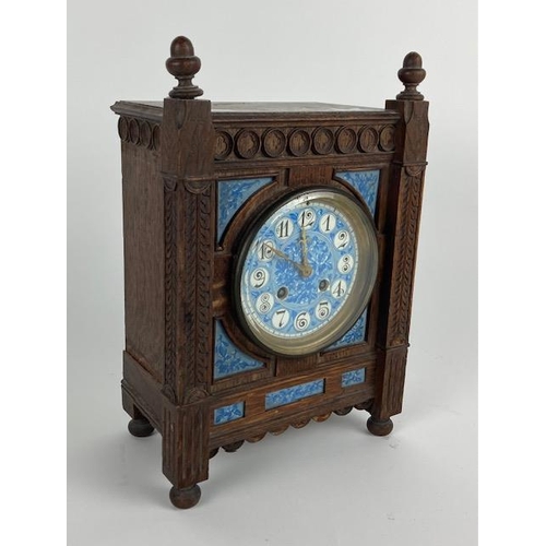 407 - An Aesthetic movement oak striking Mantel Clock, in the Gothic manner with acorn finials and a blue ... 