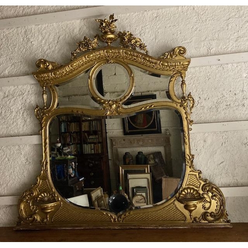 431 - A late 19th Century ornate gilt Overmantel Mirror, crested with an urn issuing floral swags on an ar... 