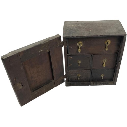 10 - An early 18th Century English oak Spice Cabinet, the panelled door with brass drop handle opening to... 