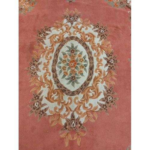 424 - A large pink ground Chinese woollen Carpet, with large central floral bouquet and conforming border,... 