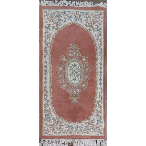 424 - A large pink ground Chinese woollen Carpet, with large central floral bouquet and conforming border,... 