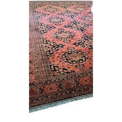 425 - An attractive Middle Eastern woollen Carpet, the centre with eleven medallions on burgundy ground in... 