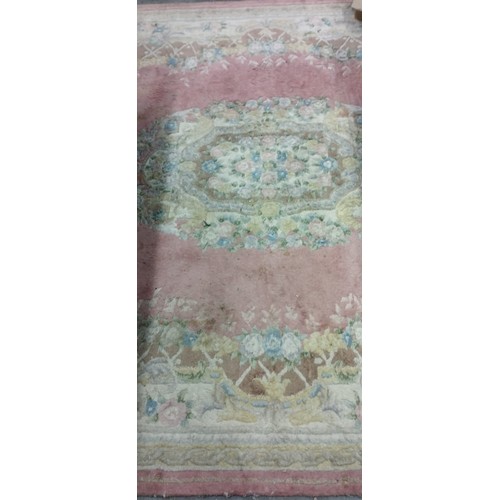 414 - A large Chinese woollen Carpet, with decorative floral medallion centre on pink ground with conformi... 