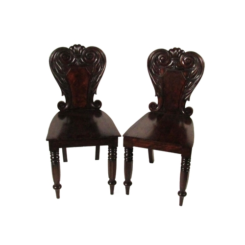 779 - A pair of William IV Irish mahogany Hall Chairs, with carved shield backs over solid seats on front ... 