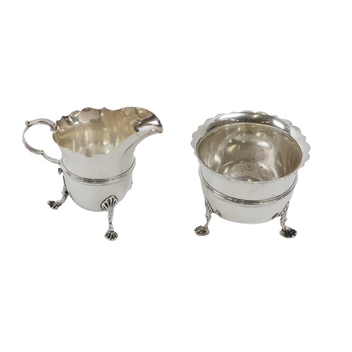 125 - An English silver Cream Jug and matching Sugar Bowl, with shaped rims, on shell pad feet, by Stokes ... 