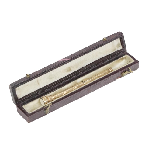 181 - A gold coloured Pocket Pencil, with a slide band to reveal the pencil, having a chased decorative en... 