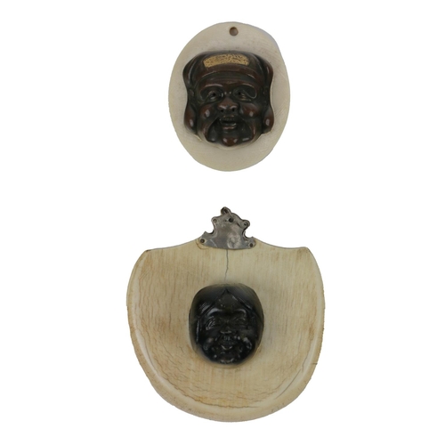 239 - Two similar small antique Japanese bronze Masks, mounted on small white shield shaped plaque. (2)... 