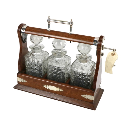 286 - An attractive Edwardian oak cased Tantalus, with silvered handle and mounts, housing three cutglass ... 