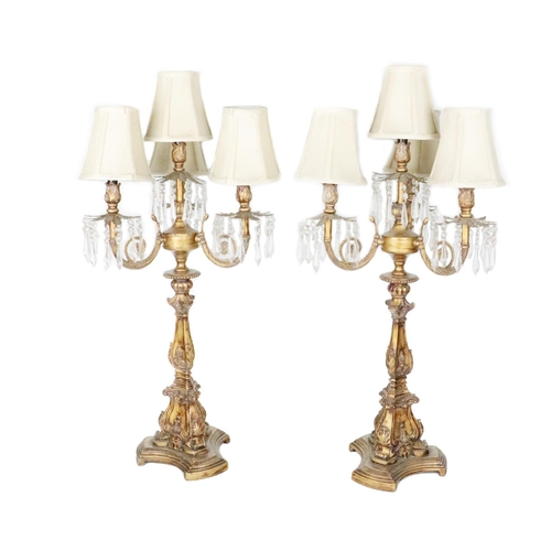 855 - A pair of assimilated giltwood three branch - four light Candelabra, (converted) each with cream sha... 