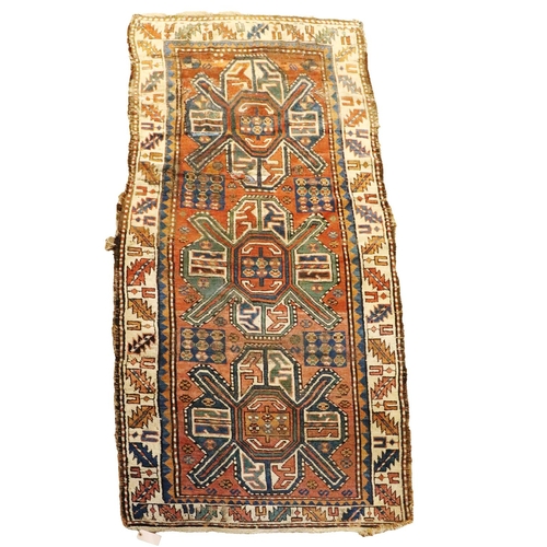 426 - An antique Middle Eastern woollen Runner Carpet, the claret ground centre with three medallions and ... 