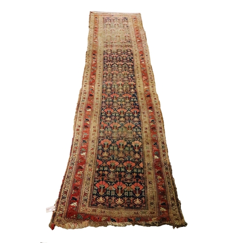 430 - A large antique Middle Eastern woollen Runner Carpet, the blue ground centre with multiple stylized ... 