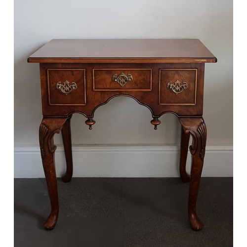 3 - A walnut low boy, the rectangular top with frieze drawer and flanking deep drawers on leaf capped ca... 