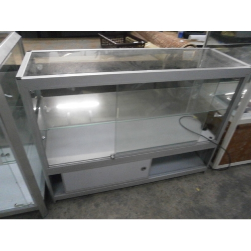 691 - A large glazed retail counter cabinet with sliding doors. Dimensions H35