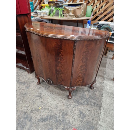 601 - A vintage flame mahogany serpentine fronted cabinet on shell carved legs