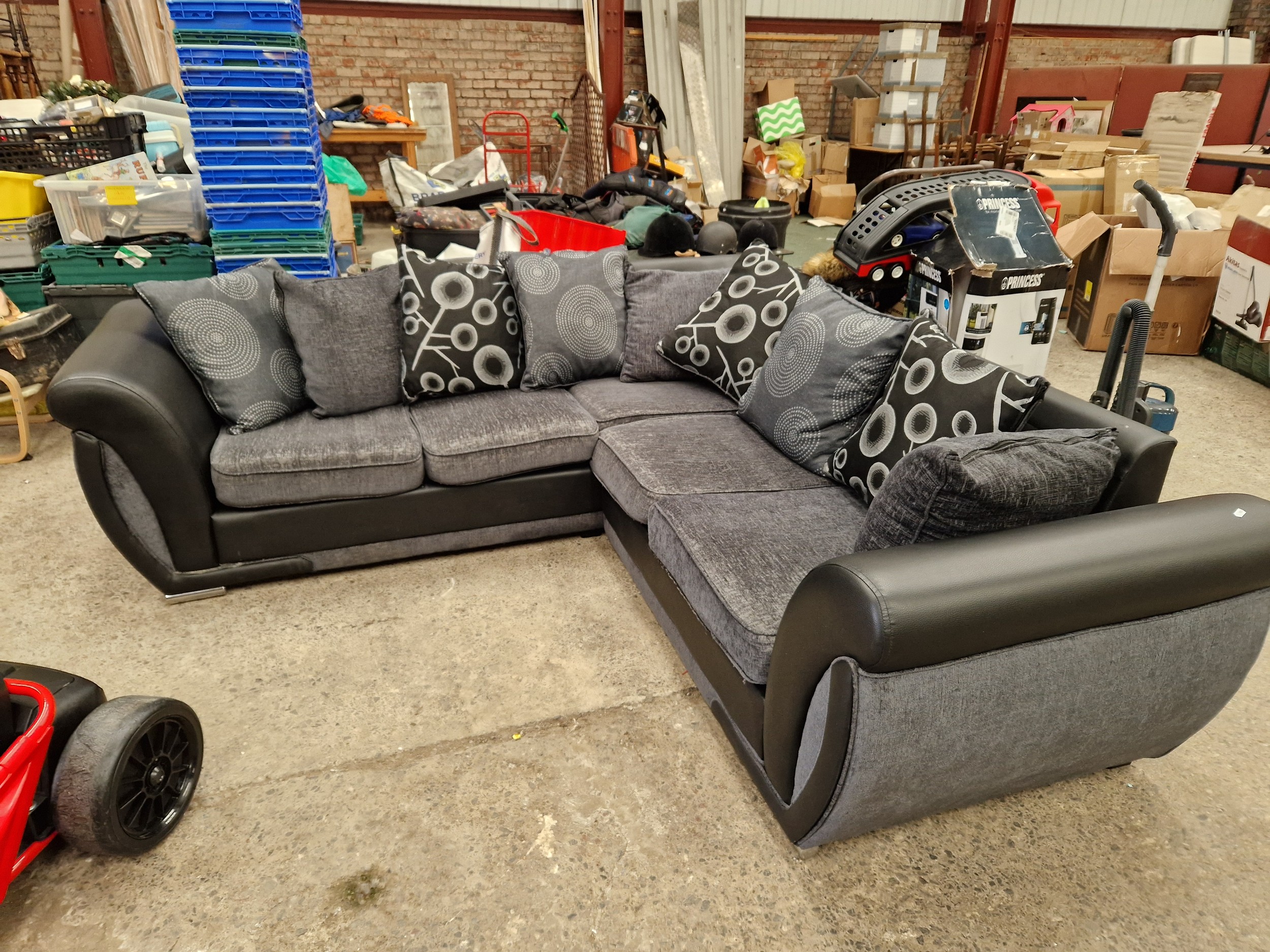 A large black faux leather corner settee unit with cushions
