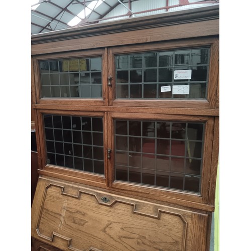 704 - A vintage oak Jacobean style 2 over 1 drawer bureau bookcase with leaded glazed upper doors