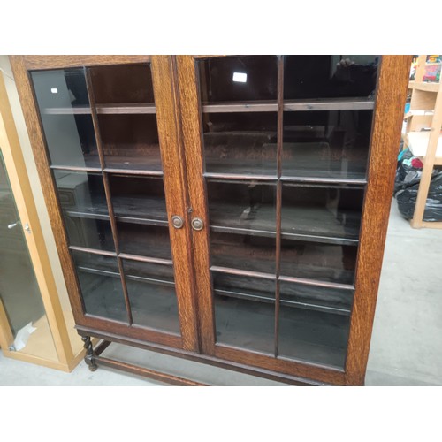 614 - A large antique oak glazed 2 door bookcase with carved decoration and Barley Twist legs