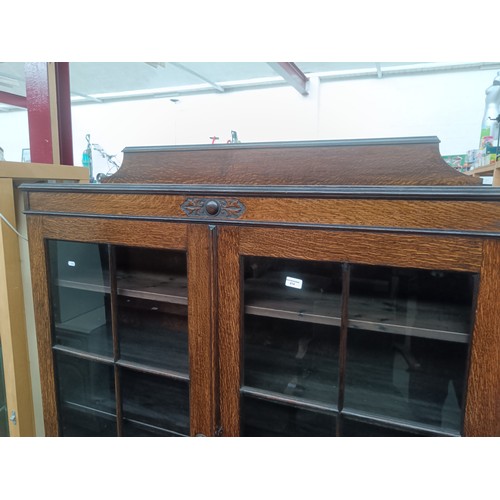 614 - A large antique oak glazed 2 door bookcase with carved decoration and Barley Twist legs