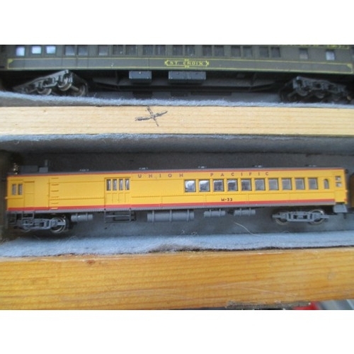 256 - Wooden display case containing miniature model rail locomotives and carriages