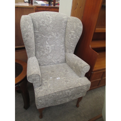 681 - An upholstered wing back fireside chair