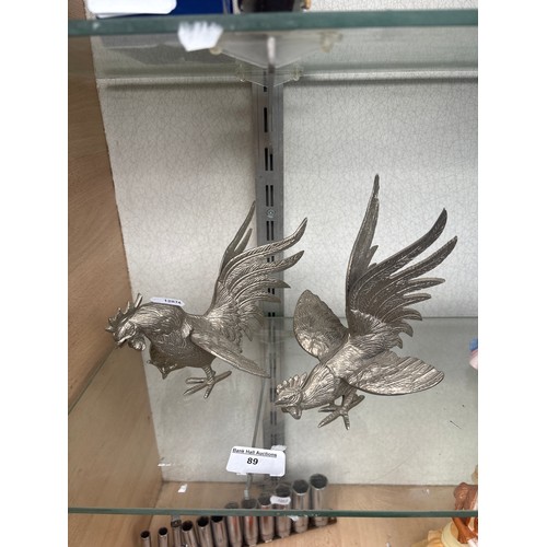 89 - Two white metal roaming roosters