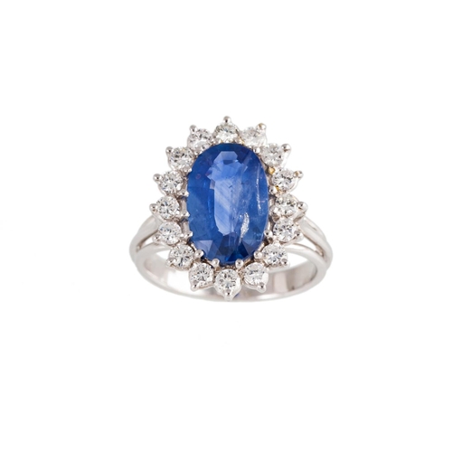 131 - A SAPPHIRE AND DIAMOND CLUSTER RING, the oval sapphire to a brilliant cut diamond surround, mounted ... 