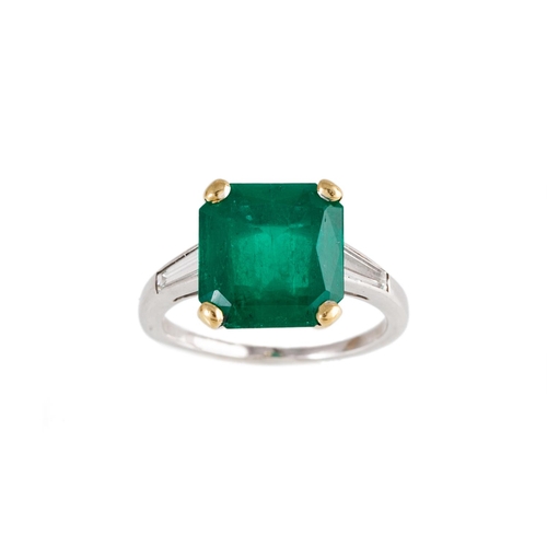 163 - A SINGLE STONE EMERALD RING, the octagonal cut emerald to tapered baguette diamond shoulders, mounte... 