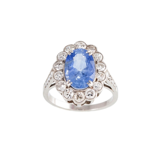 179 - A DIAMOND AND SAPPHIRE CLUSTER RING, the oval sapphire to a brilliant cut diamond surround, mounted ... 