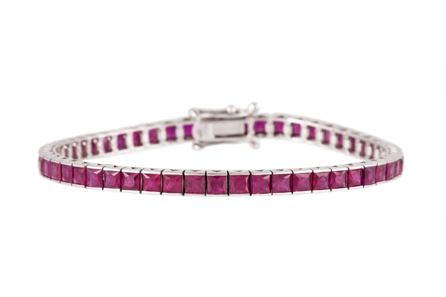 A RUBY LINE BRACELET, set with square step cut rubies, channel set