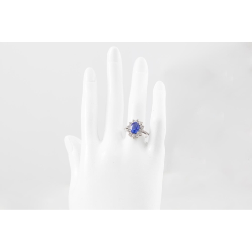 11 - A TANZANITE AND DIAMOND CLUSTER RING, the oval tanzanite to a brilliant cut diamond surround, mounte... 