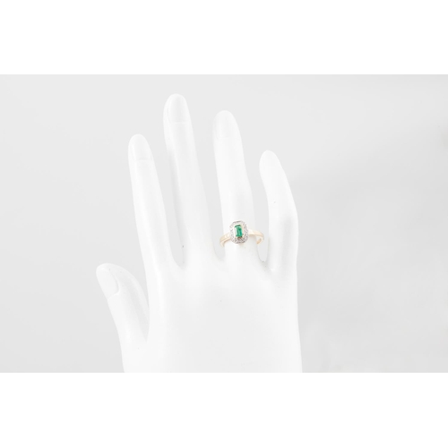 231 - AN EMERALD AND DIAMOND RING, the trap cut emerald to a diamond surround, mounted in yellow gold, siz... 