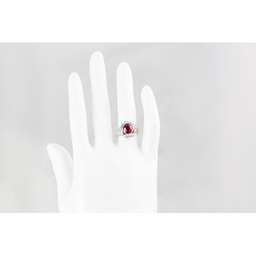 247 - A RUBY AND DIAMOND CLUSTER RING, in the Art Deco style, the oval ruby to a diamond surround and shou... 