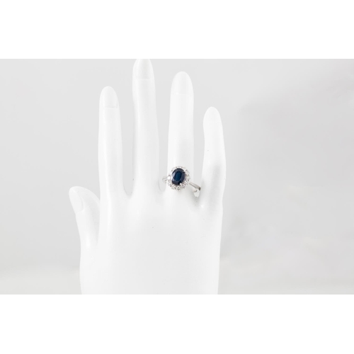 25 - A DIAMOND AND SAPPHIRE CLUSTER RING, the oval sapphire to a brilliant cut diamond surround, mounted ... 